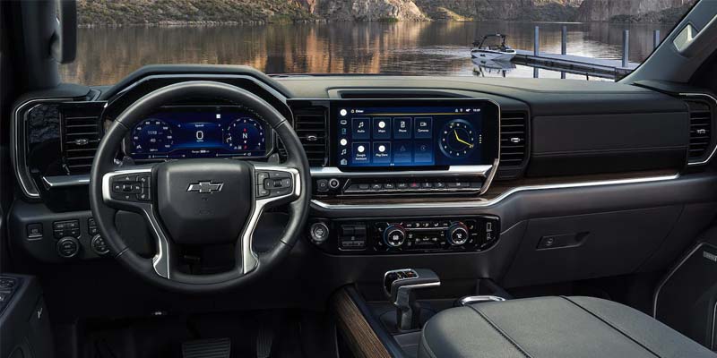 The cabin view of a Chevy Silverado 1500, showcasing the steering wheel, dashboard, and interior controls.