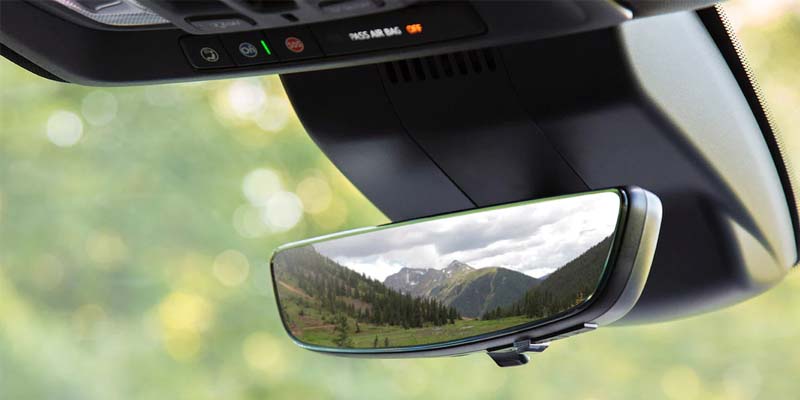 The rearview mirror of a Chevrolet Silverado 1500, reflecting the mountain view behind.