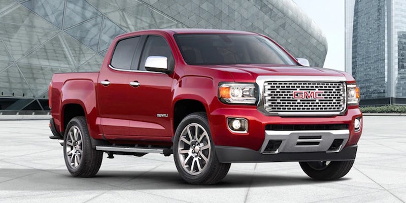 A red GMC Canyon shown in a side profile, highlighting its sleek design and rugged features.