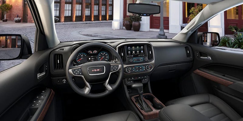 The front cabin dashboard of a GMC Canyon, showcasing the steering wheel, display screen, and control panels.
