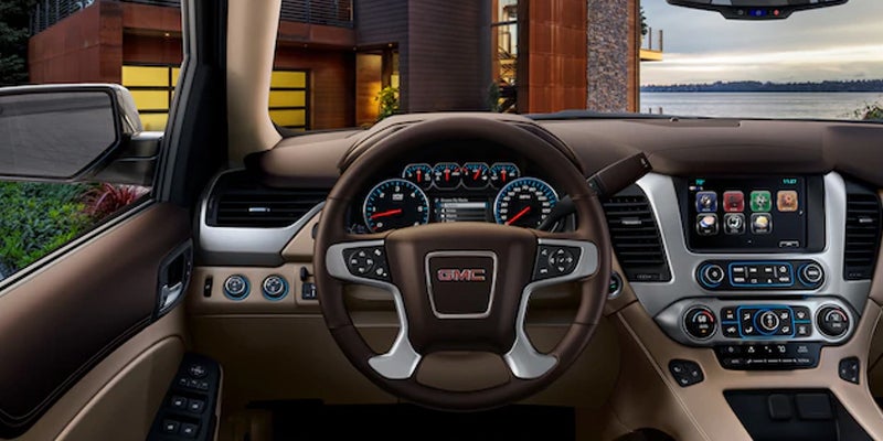 The steering wheel and dashboard of a 2019 GMC Yukon, showcasing the controls, display, and interior design.