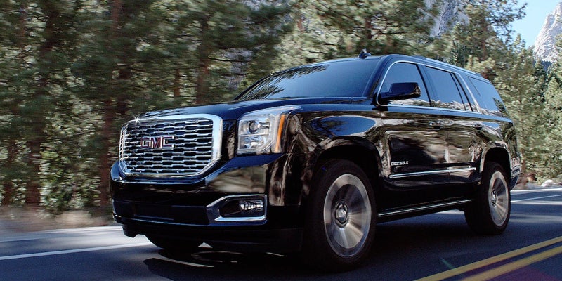 A black 2019 GMC Yukon driving on the road, showcasing its sleek design and smooth motion.