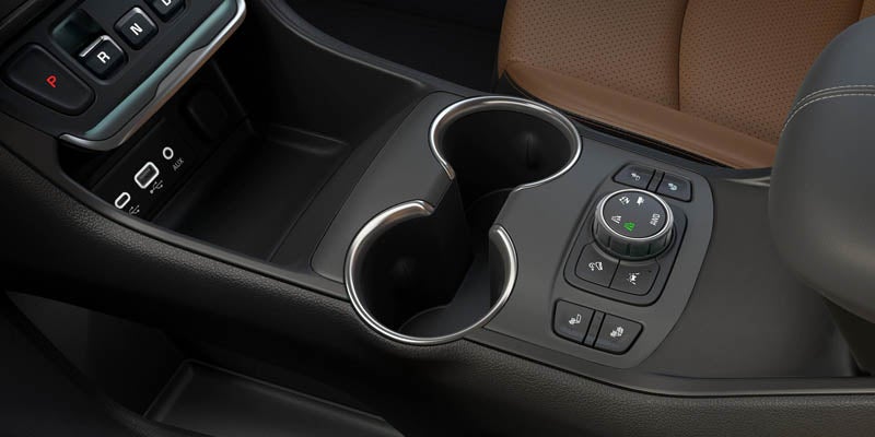 The cupholder and control buttons in the interior of a GMC Terrain, showcasing the center console and nearby features.