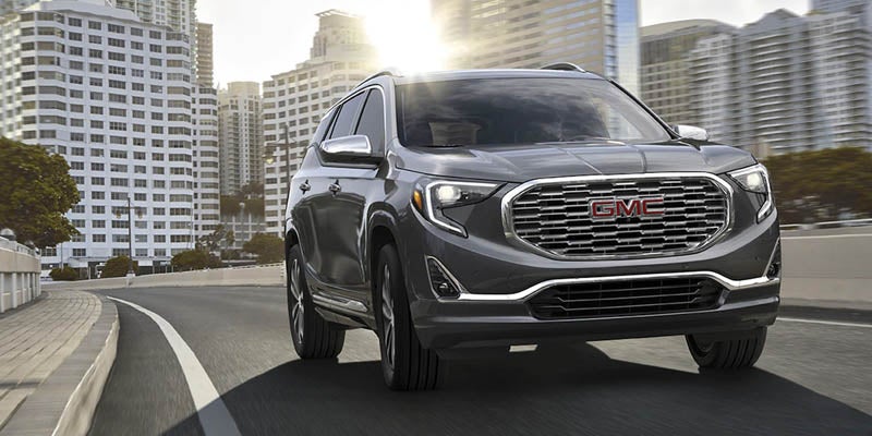 A GMC Terrain driving on a road, showcasing its smooth motion and sleek design as it travels through the landscape.