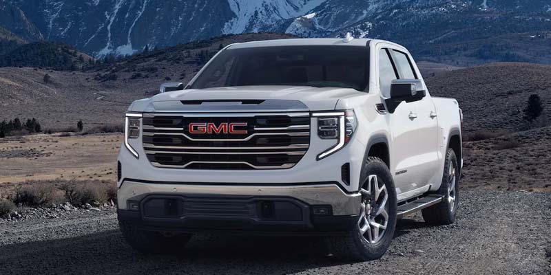 white GMC Sierra 1500 parked in front of a stunning mountain range