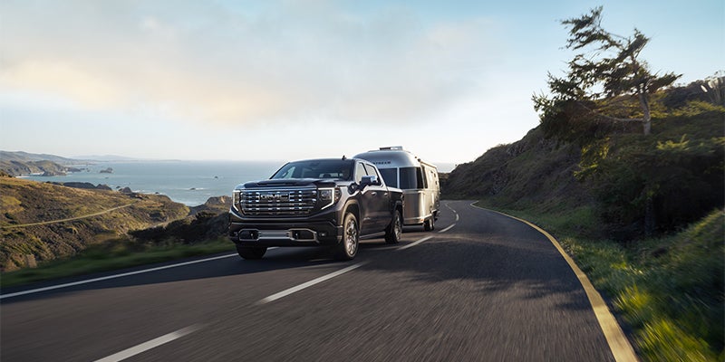 GMC Sierra 1500 towing a container on the road, showcasing its towing capacity and strength.