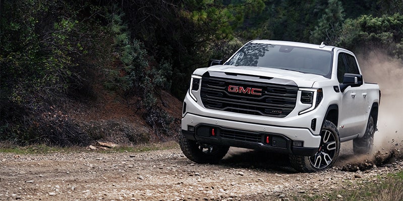 white GMC Sierra 1500 powering through a rough drive, demonstrating its tough performance