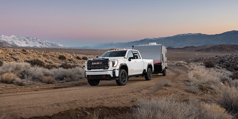 A White GMC Sierra HD pickup truck towing in a sandy area